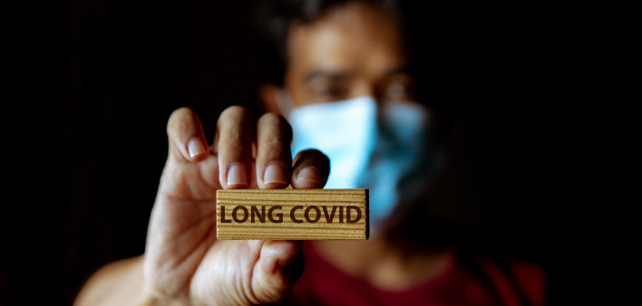 Masked Asian man show wooden sign with wording "Long Covid"