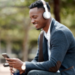Shot of a young businessman using a smartphone and headphones in the city