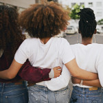 Rearview shot of a group of unrecognizable young friends walking with their arms around each other in the city