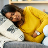 Shot of a young woman suffering from stomach cramps at home